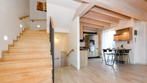 Una escalera que lleva al segundo piso, una cocina con electrodomésticos modernos y un comedor con taburetes de bar.