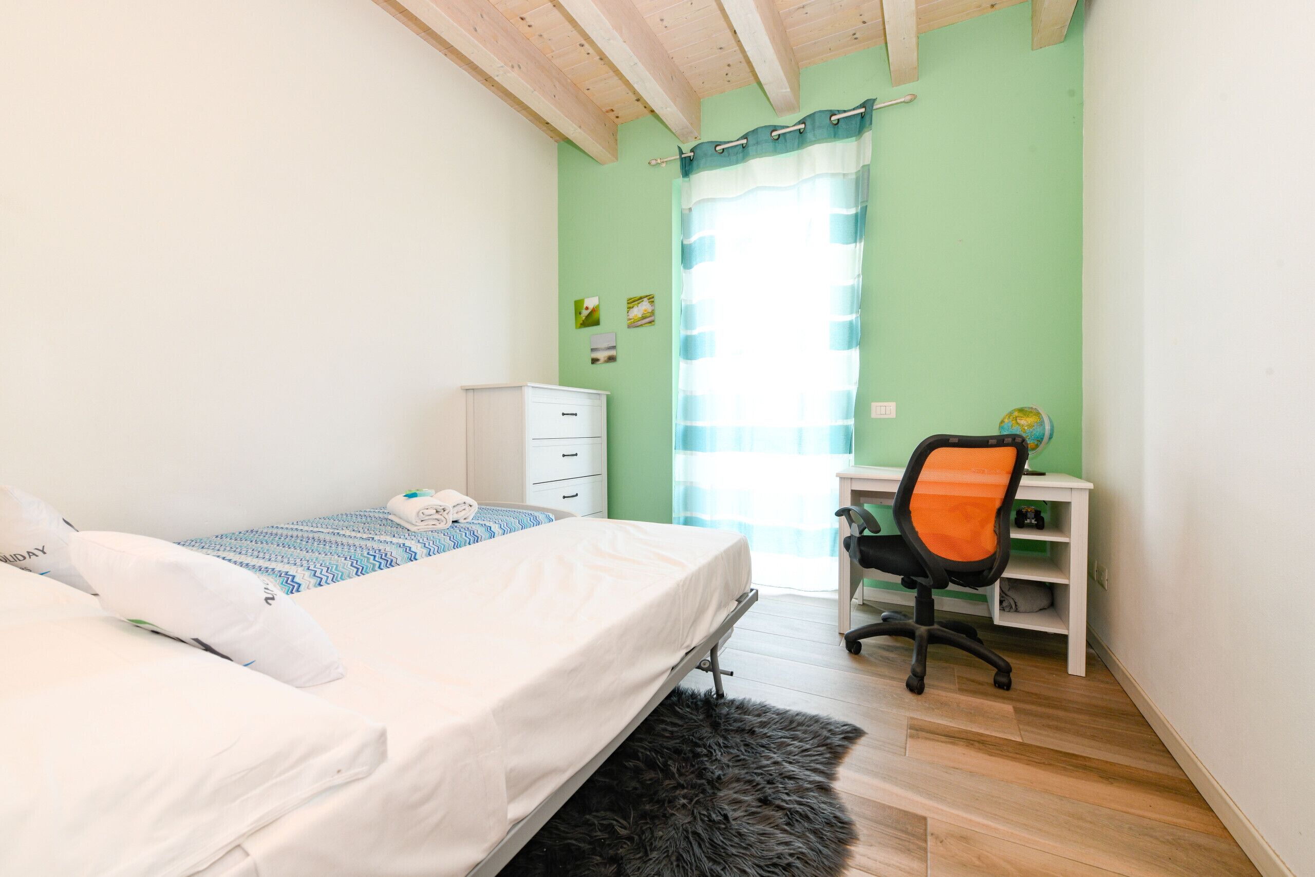 Een slaapkamer met een bed, een bureau en een stoel.