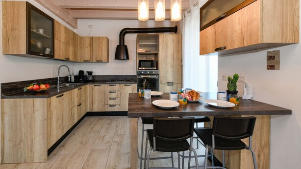 Una cocina moderna con armarios de madera, una isla central con sillas y electrodomésticos integrados.