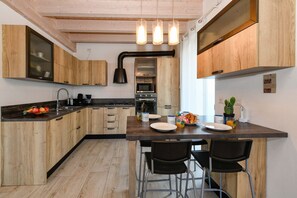 A modern kitchen with wooden cabinets, a central island with chairs, and built-in appliances. - MGH- Dama Family Home Peschiera (Peschiera del Garda)