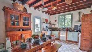 A kitchen with wooden cabinets, a large wooden table, and a brick wall. - Private estate with swimming pool, garden & open spaces - Up to 12 guests (Bréville)