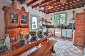 A kitchen with wooden cabinets, a large wooden table, and a brick wall. - Private estate with swimming pool, garden & open spaces - Up to 12 guests (Bréville)
