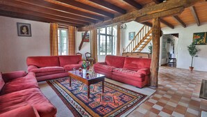 A spacious living room with red sofas, a wooden coffee table, and a patterned rug. - Private estate with swimming pool, garden & open spaces - Up to 12 guests (Bréville)