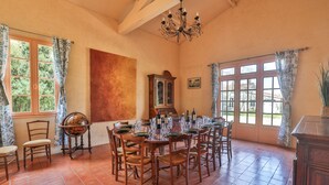 A dining room with a large wooden table set for six, surrounded by chairs, with a grandfather clock and a large window with curtains. - Private estate with swimming pool, garden & open spaces - Up to 12 guests (Bréville)