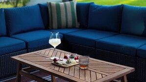 Una mesa de madera con una copa de vino blanco, cuencos con fruta y un vaso de jugo de naranja.