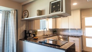 Una cocina moderna con armarios blancos, encimera negra y estufa integrada.