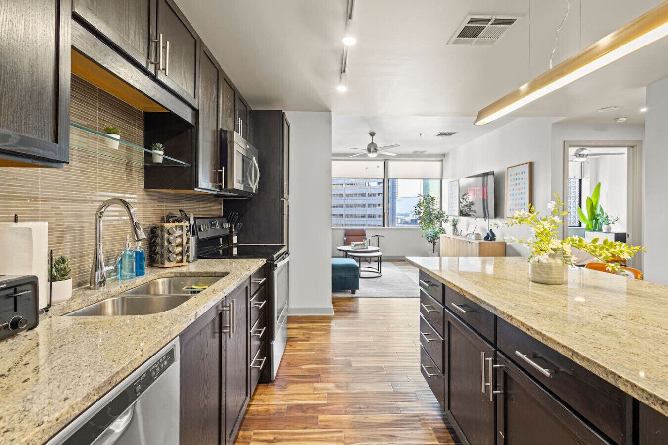A modern kitchen with dark cabinetry, granite countertops, and a central island.