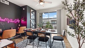 A modern dining area with a black and white zebra-patterned rug, a ceiling fan, and a neon sign on the wall. - 2BR Modern Stay • Walk to AA Center• Free Parking (Dallas)