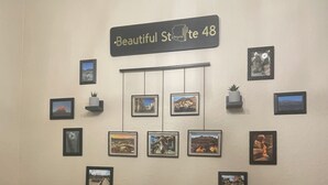Eine Wand mit einem Schild, auf dem 'Beautiful St. 48' steht, und mehreren in einem Raster angeordneten gerahmten Bildern.