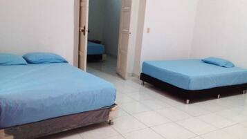 A room with two beds, one larger and one smaller, both with blue bedding.