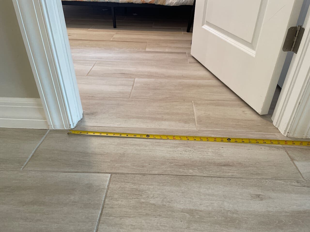 A hallway with a measuring tape on the floor, indicating a space for flooring installation.