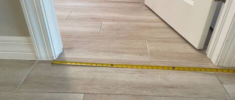 A hallway with a measuring tape on the floor, indicating a space for flooring installation.