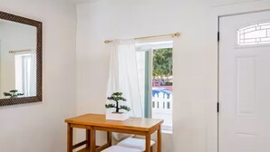 Una habitació amb taula de fusta i dues cadires, una finestra amb cortina i una porta.