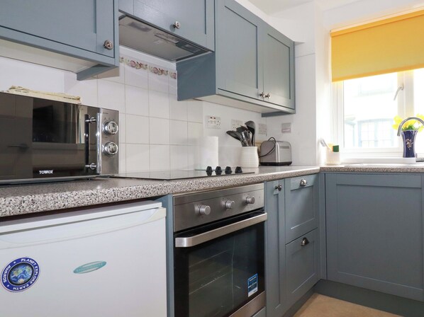 A kitchen with grey cabinets, a stainless steel microwave, a built-in oven, and a toaster on the countertop.