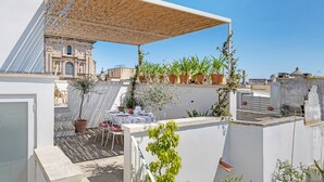 En tagterrasse med pergola, plantekasser, spisebord og stole.