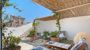 En tagterrasse med plantekasser, et træbeklædt pergola og udsigt til historisk arkitektur.