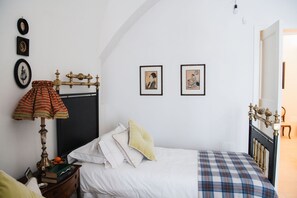 Une chambre à coucher avec un lit, une table de chevet, une lampe et deux tableaux encadrés accrochés au mur.