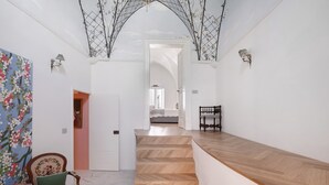 Ein Flur mit einer Holztreppe, einem Sessel mit Büchern und einer Wand mit einem Blumenbild.