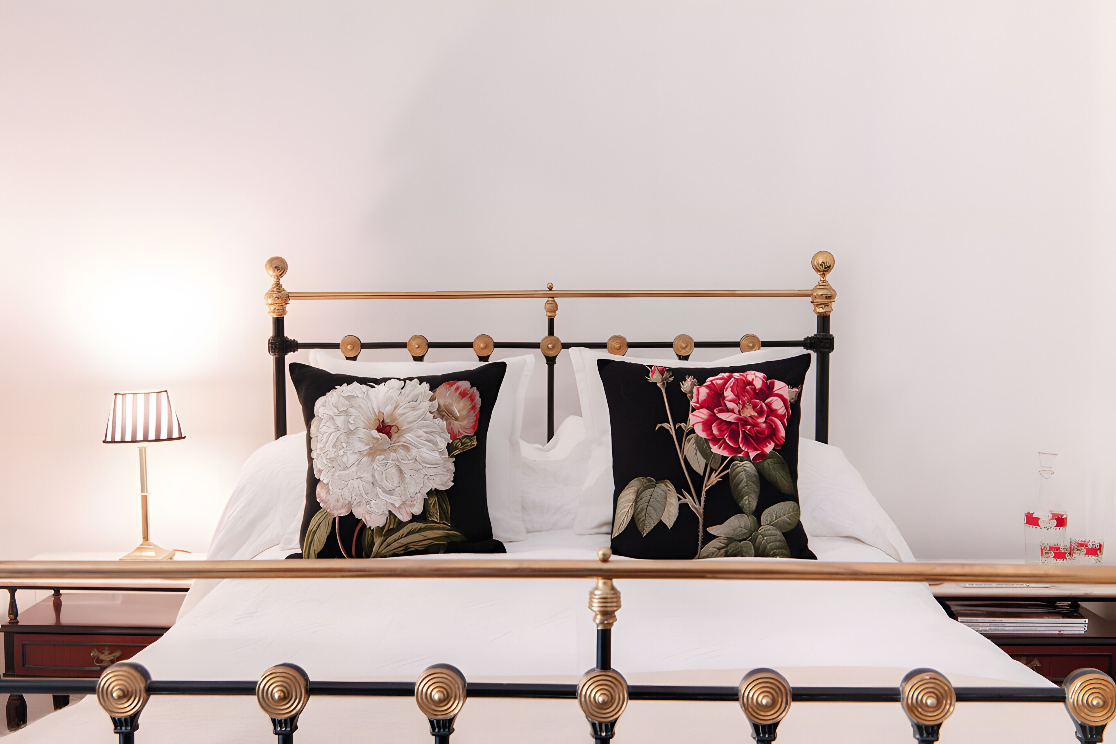 A bed with a black metal frame, white bedding, and two pillows with floral designs.