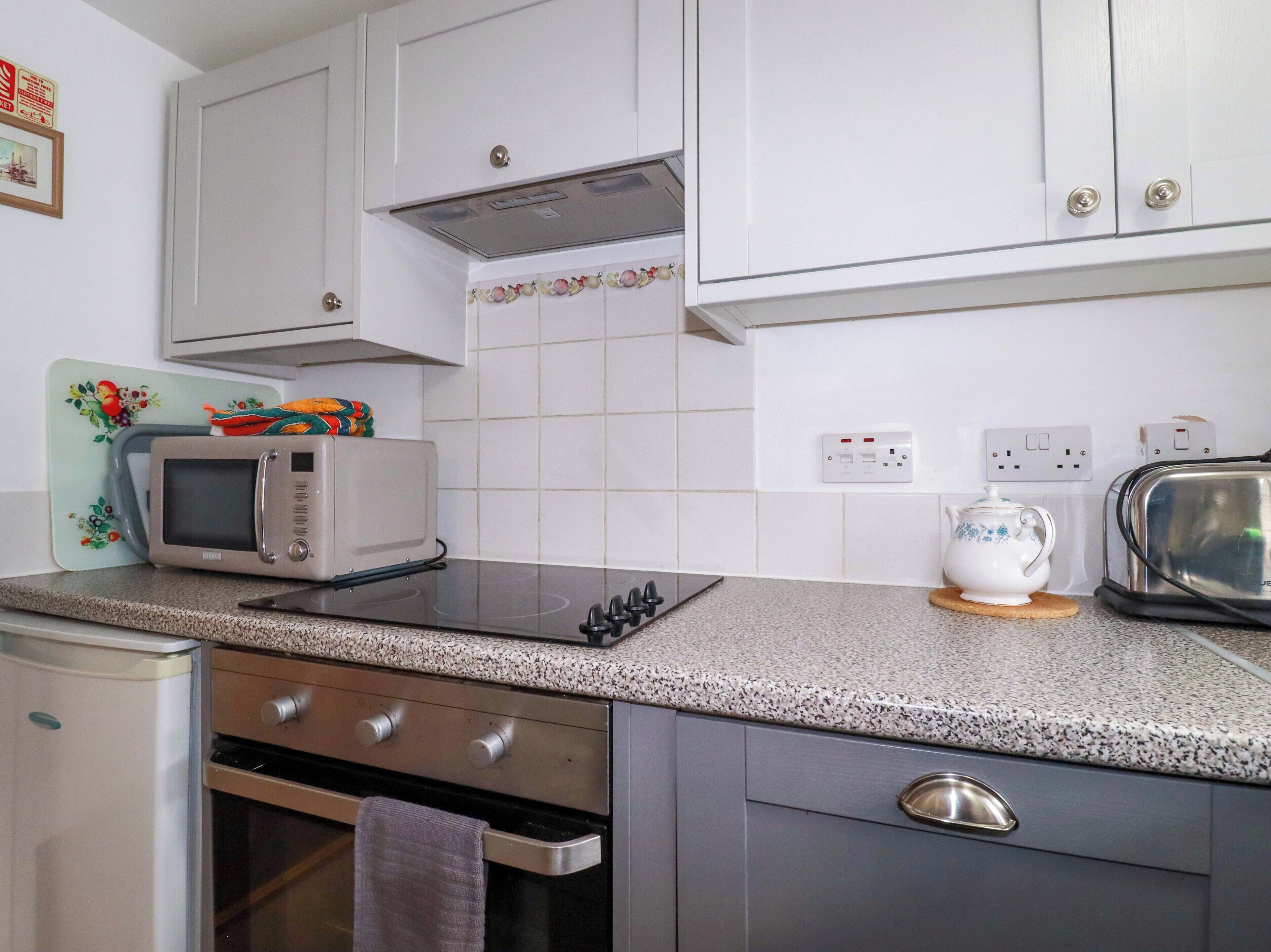 A kitchen with white cabinets, a microwave, a toaster, and a kettle.