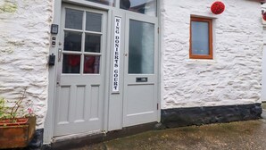 A white building with a double door, a window, and a small balcony. - The Penthouse (Looe)