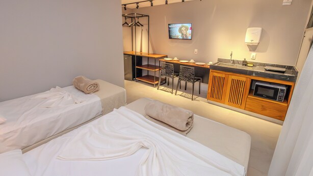 A hotel room with two beds, a small kitchenette, a TV, and a seating area.
