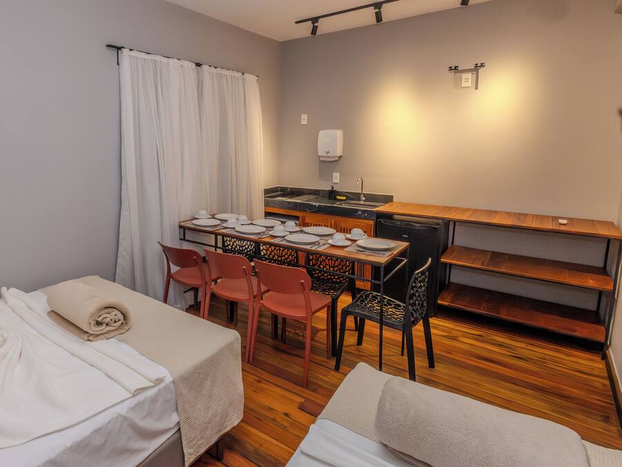 A small, compact room with a bed, a table set for dining, and a kitchenette.