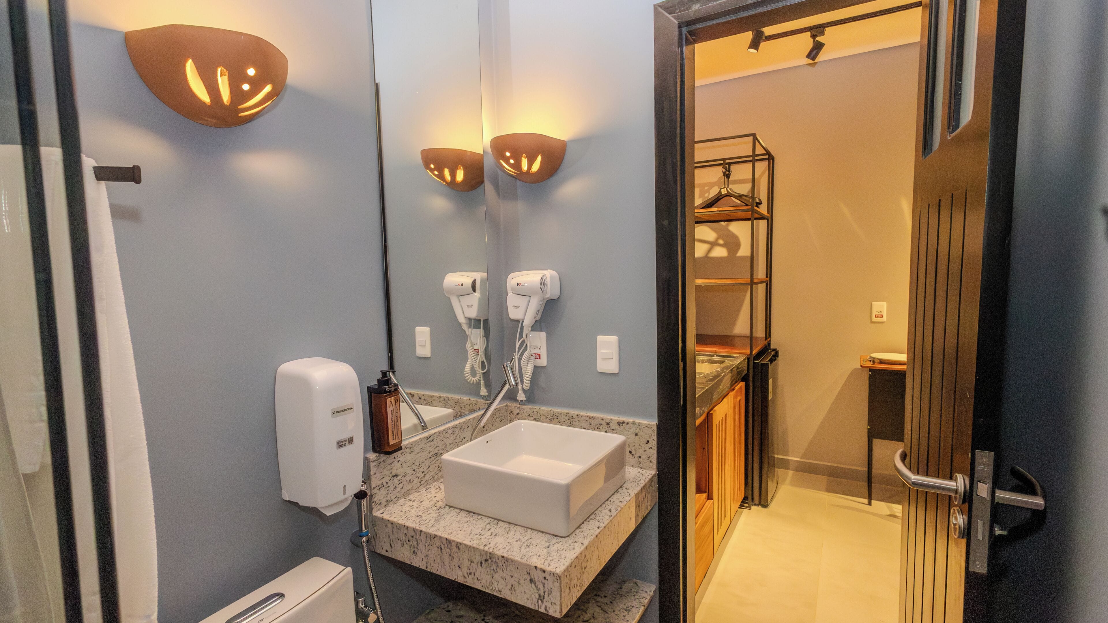 A modern bathroom with a sink, towel dispenser, and hair dryer.
