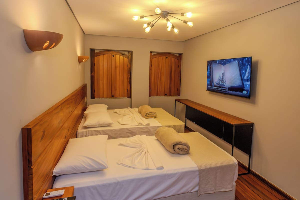 Ett hotellrum med två sängar, en TV, en taklampa och träpanel på väggarna.