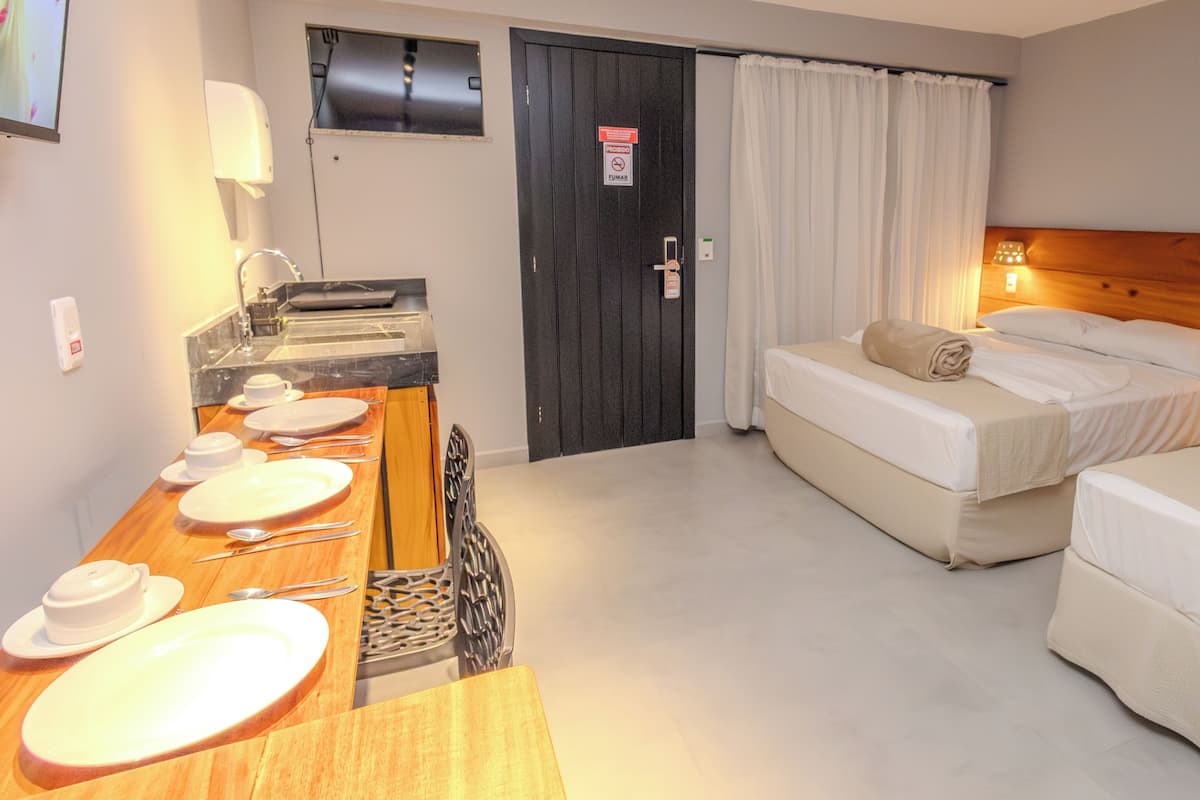 Ett hotellrum med en säng, ett skrivbord med en stol, ett matbord med tallrikar och bestick samt en dörr med en skylt.