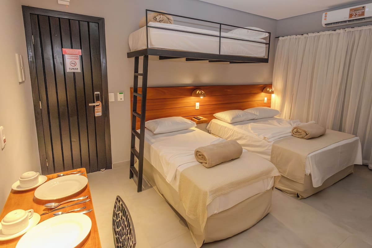 Ett hotellrum med en våningssäng, två enkelsängar, ett träbord med tallrikar och bestick samt en dörr med en skylt som säger ”Rökning förbjuden”.