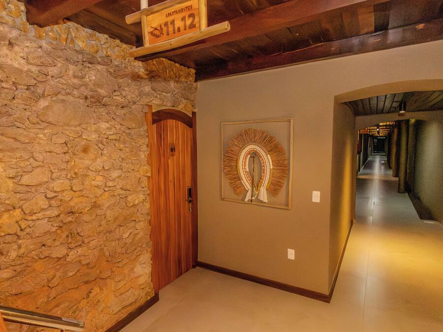 A hallway with a stone wall, wooden door, and a framed wall decoration.