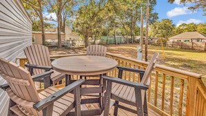A wooden deck with a round table and four Adirondack chairs. - Easy living lodge, large yard and parking area-heart of Murrells Inlet (Murrells Inlet)