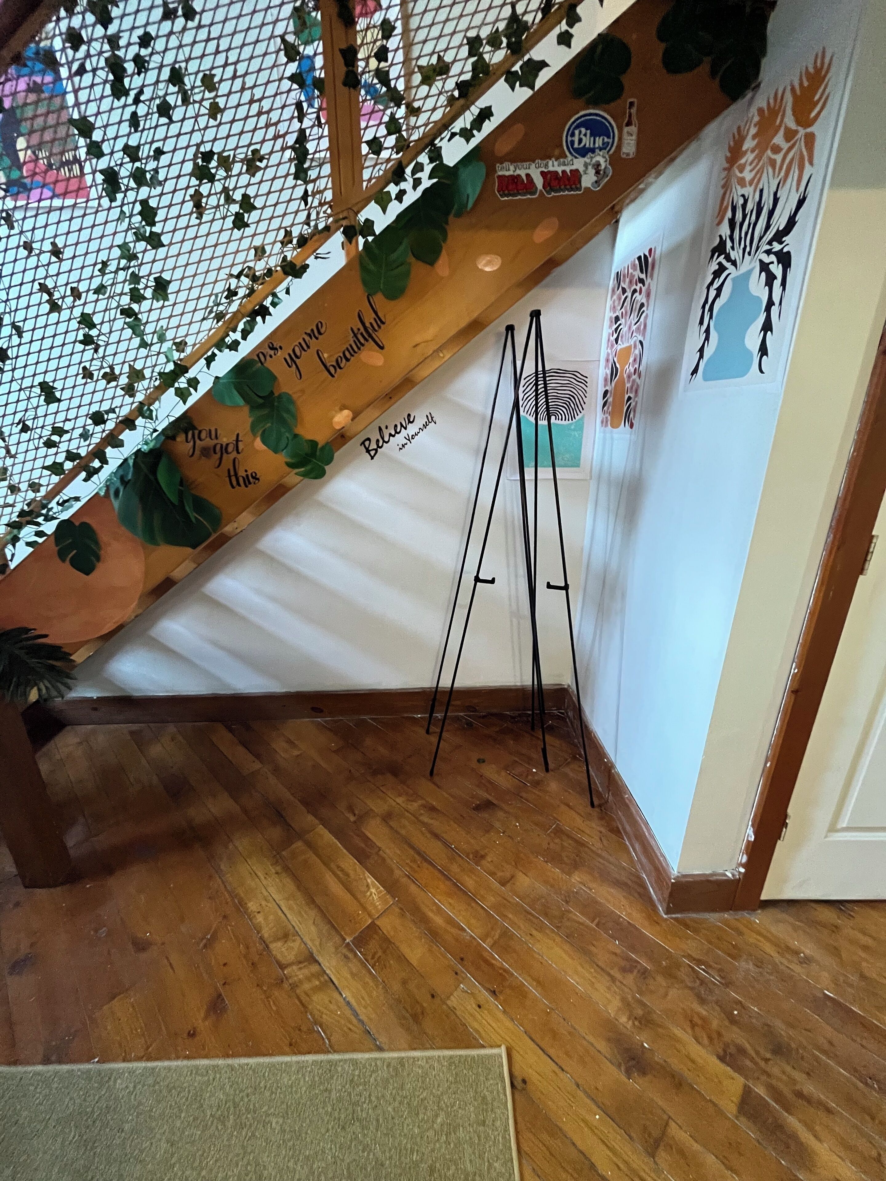 A wooden staircase with a white wall and a small easel.