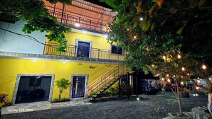 A two-story building with a yellow facade, a balcony, and a staircase leading to the upper floor.