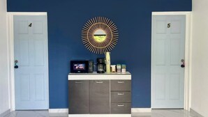 A hallway with two doors labeled 4 and 5, a white cabinet with drawers, a coffee maker, and a television on the cabinet.