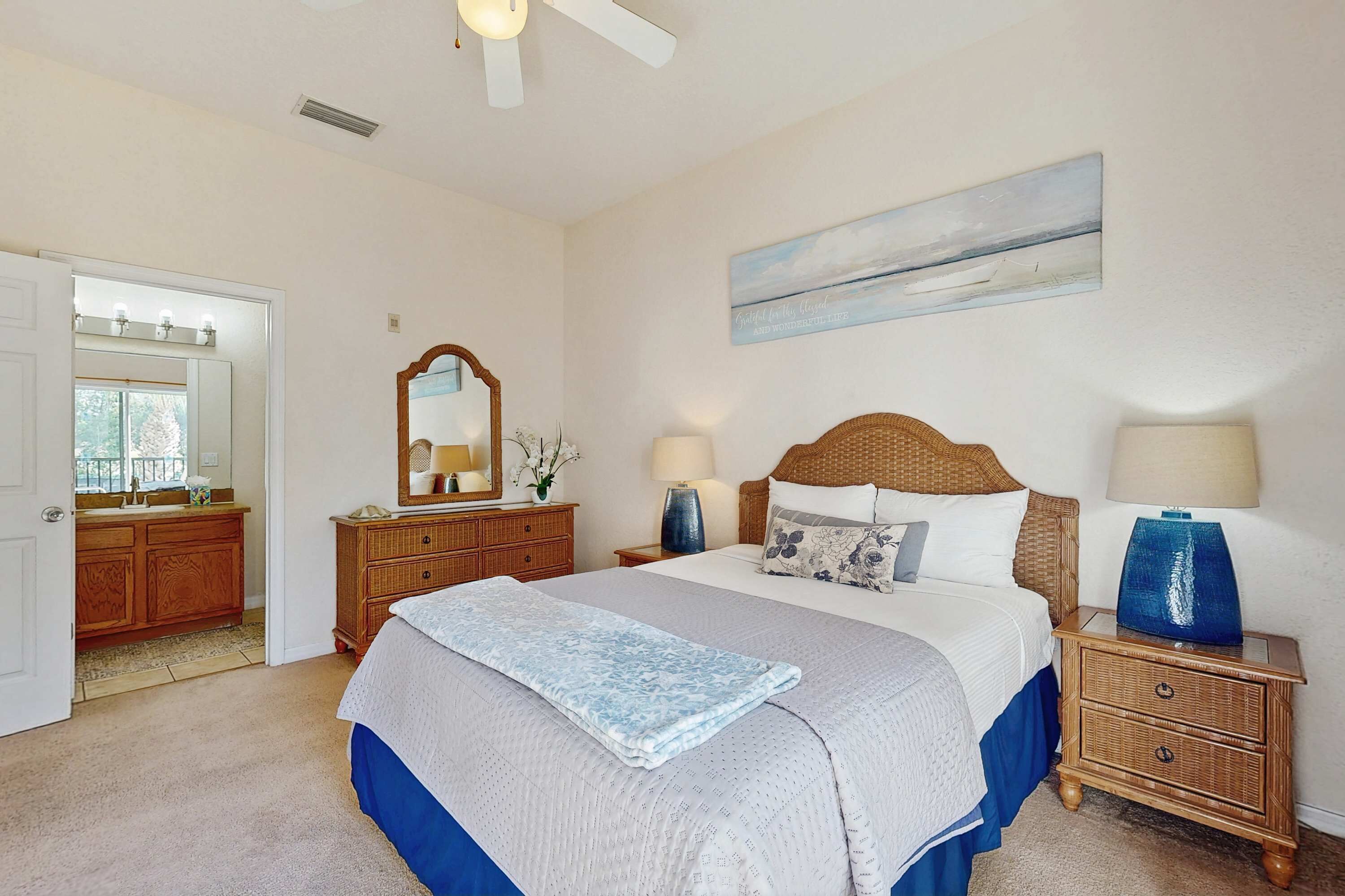 A bedroom with a large bed, a dresser, a mirror, bedside lamps, and a painting on the wall.