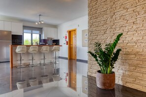 A modern kitchen with stainless steel appliances, a bar area with stools, and a stone accent wall. - Oasis do Sol, a Home in Madeira (Ponta do Sol)