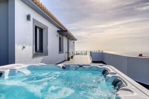 Un espace piscine sur le toit, doté d’un jacuzzi, une terrasse avec vue sur la mer et un bâtiment avec un toit en tuiles.