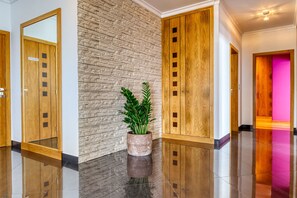 A polished lobby with a stone wall, wooden doors, and a potted plant. - Oasis do Sol, a Home in Madeira (Ponta do Sol)