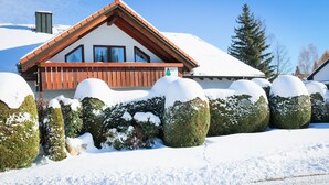 Eine Chalet mit geneigtem Dach, Holzbalkon und verschneiter Umgebung.