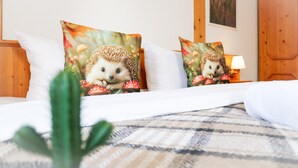 Ein Bett mit zwei dekorativen Kissen mit Igeln, einer Lampe und einem Holzschrank.