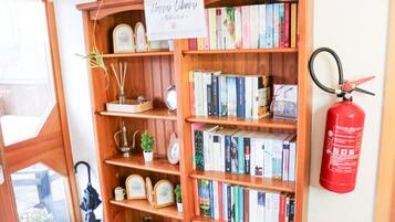 Ein Bücherregal mit Büchern, ein Feuerlöscher und ein Schild mit der Aufschrift 'Happy Library'.