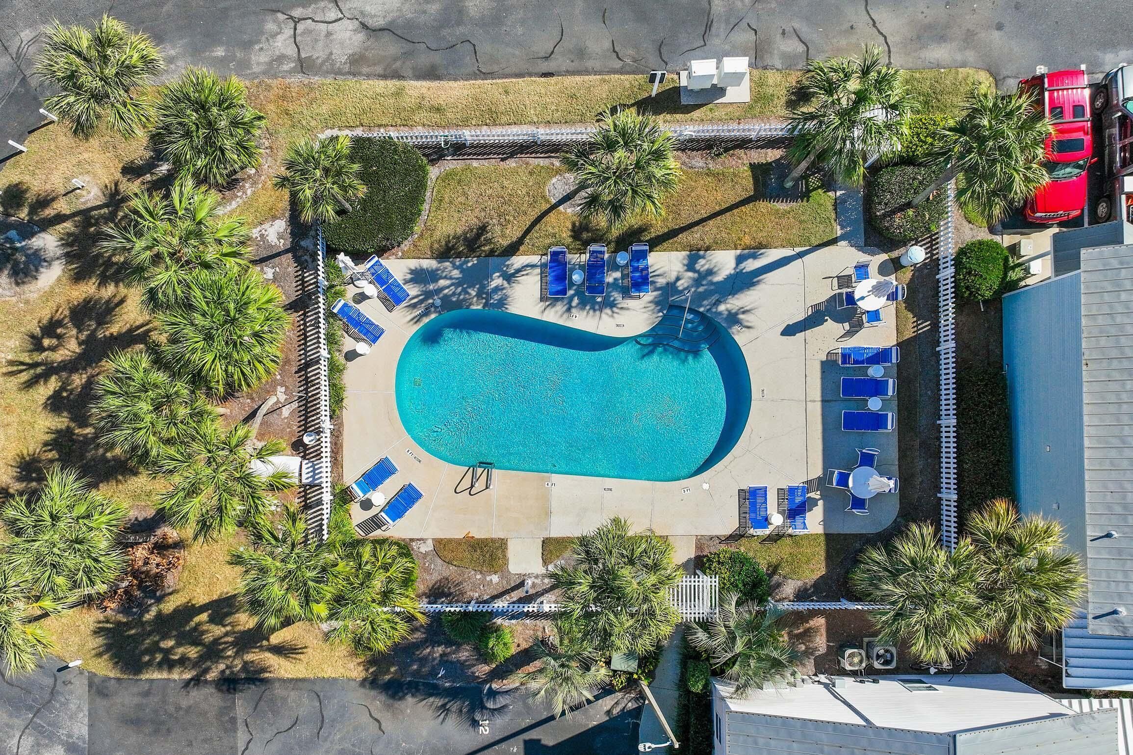 An aerial view of a swimming pool area with lounge chairs and palm trees.