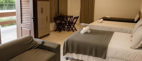 A hotel room with two beds, a sofa, a table, and a chair.