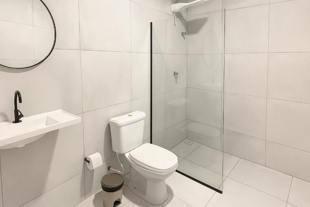 A modern bathroom with a toilet, sink, and glass shower enclosure.