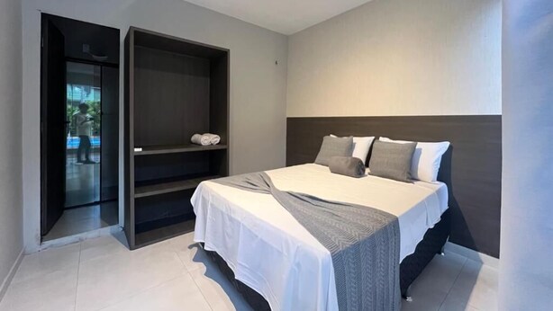 A modern bedroom with a bed, a wardrobe, and a door leading to a balcony. - Pousada Jardins (São Luís)