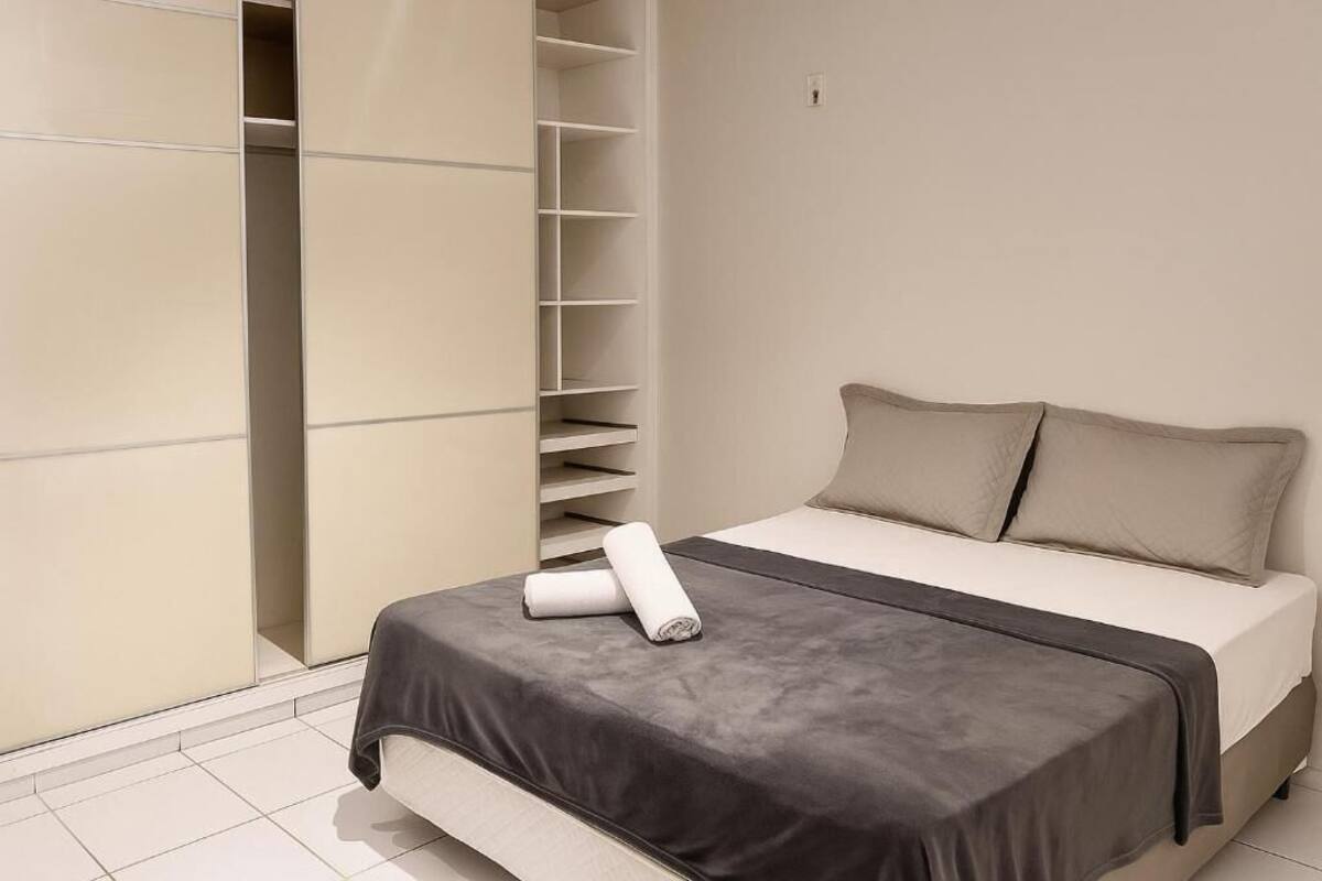 A bedroom with a bed, a wardrobe, and a built-in shelf unit.