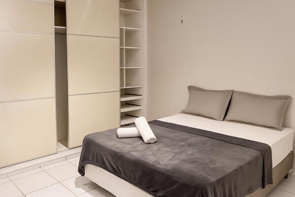 A bedroom with a bed, a wardrobe, and a built-in shelf unit. - Pousada Jardins (São Luís)