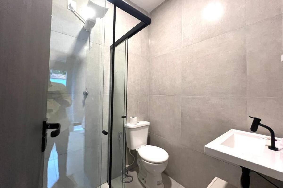 A modern bathroom with a glass shower enclosure, a toilet, and a sink.